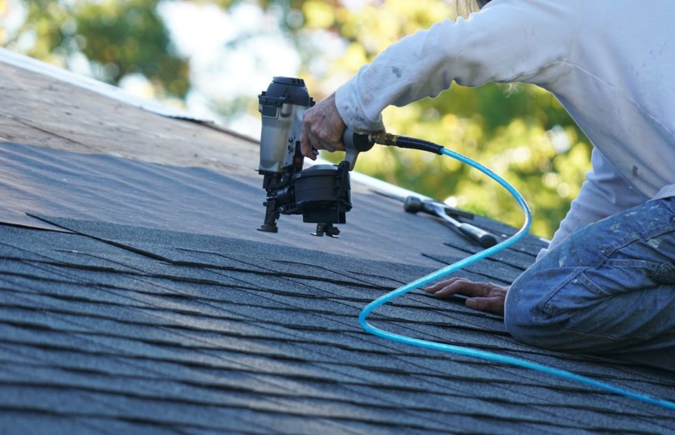 A Roofing Expert Installing Single Ply Shingles to a Roof Using a Nailing Power Tool