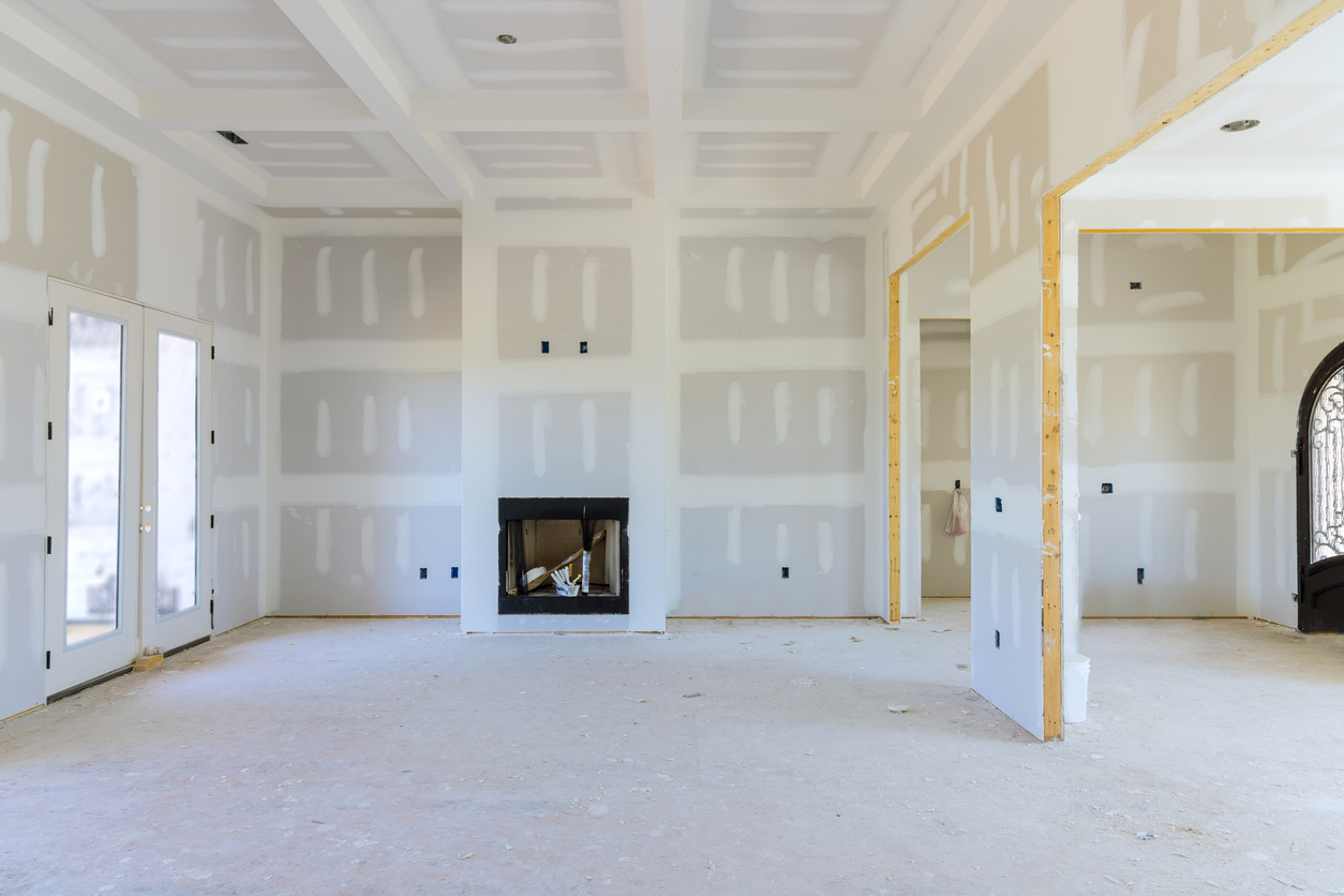 A large, empty room with unfinished drywall applied to the walls