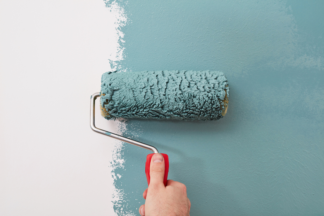 A paint roller putting a fresh coat of paint on an interior wall