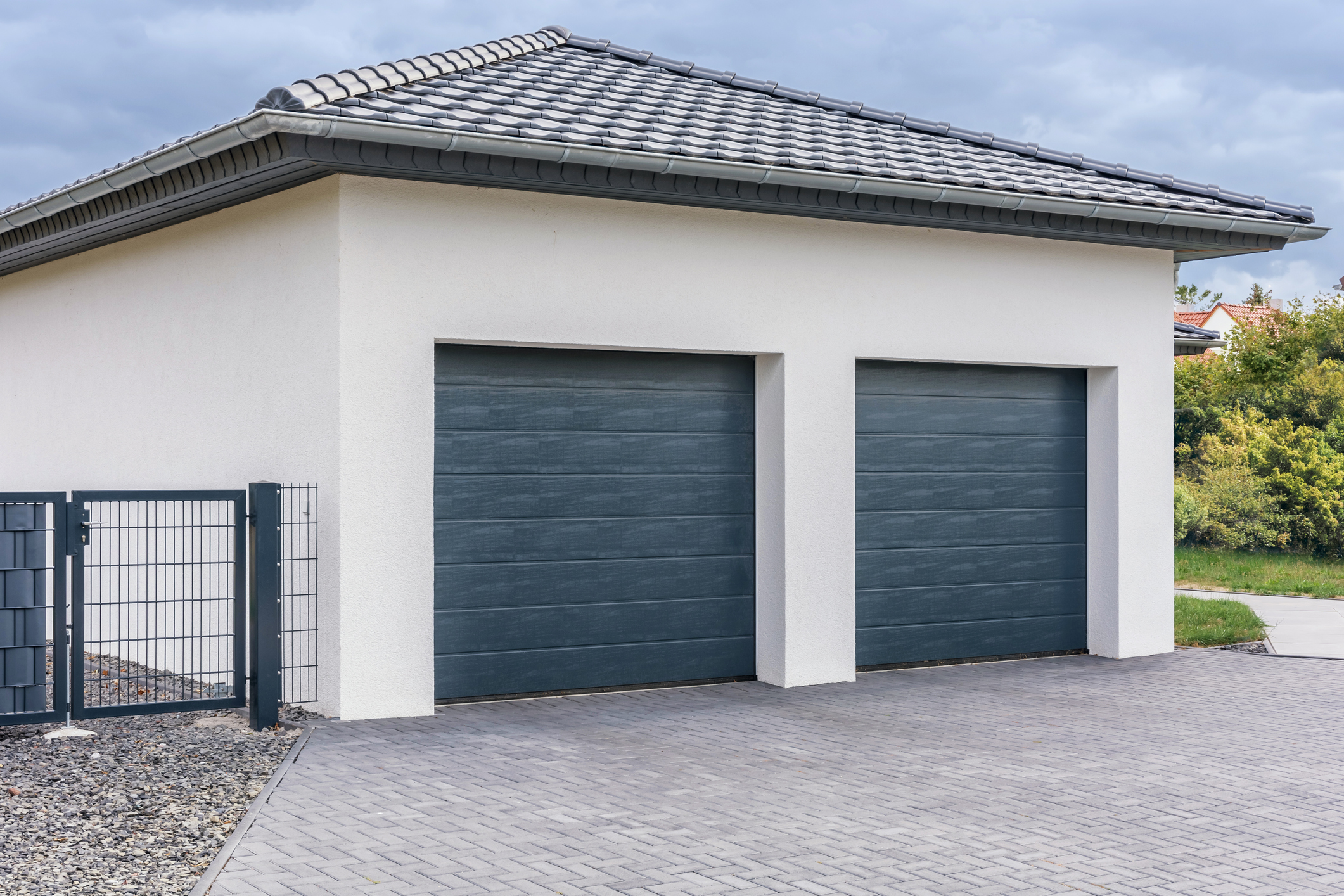 A two car garage detached from the home with a stone driveway that leads up to it and water friendly landscaping around it