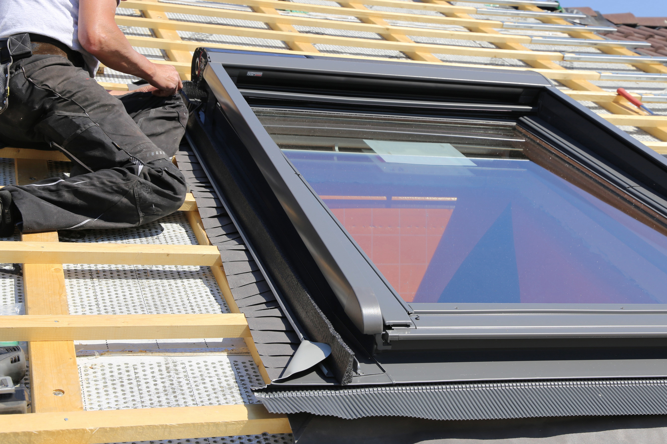 A skylight being installed by someone on an incomplete roof 