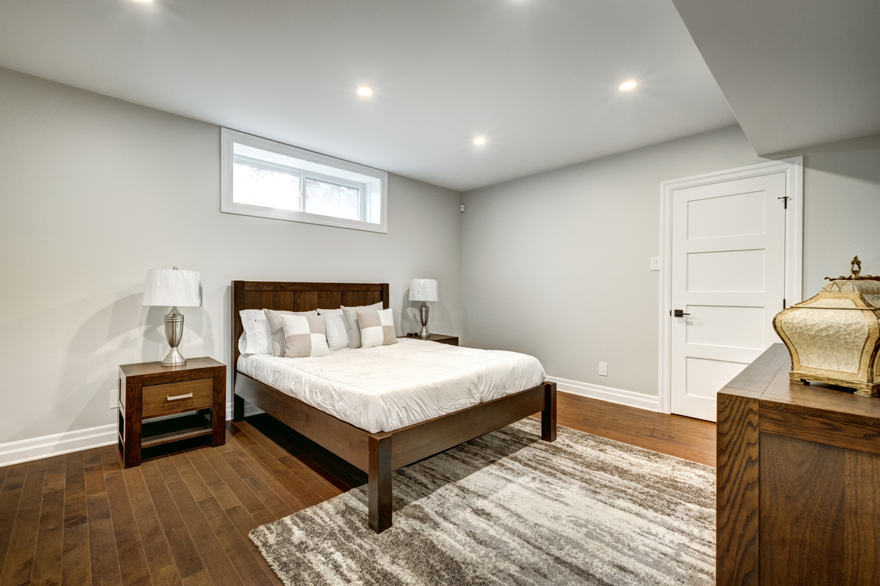 A basement bedroom remodeled with new walls and wood flooring