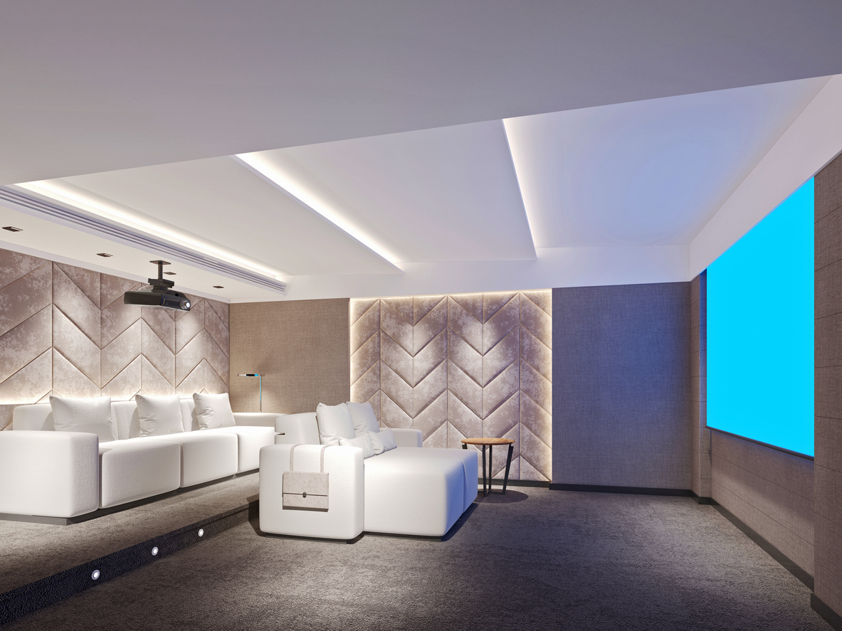 A basement entertainment system and theater room with couches, a projector, and sound dampening walls