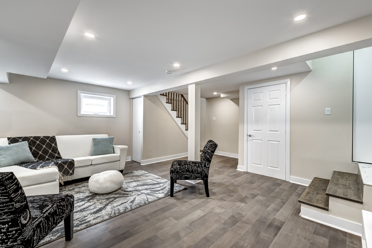 A beautiful, finished Colorado Springs basement with clean, modern wood floors, white walls, and neat furniture