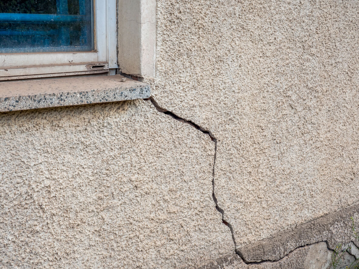 A large crack running through the exterior stucco of a house