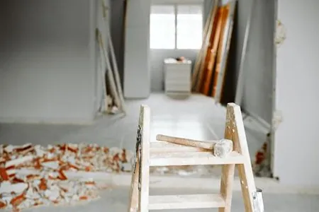 Residential Demolition & Interior Demolition Experts wooden ladder with a hammer on it and demolished wall in the background