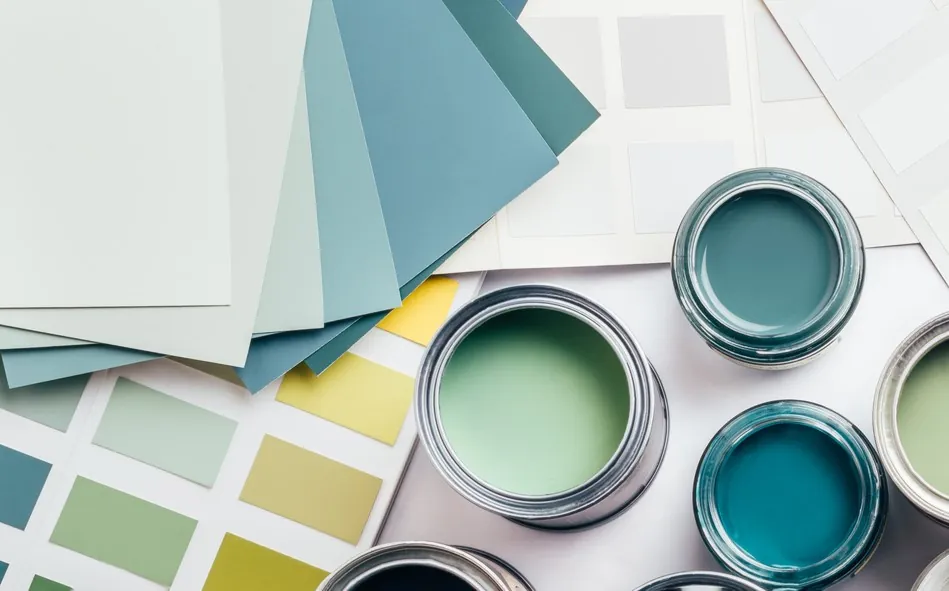 Open paint cans, colored papers, and paint samples laid out artistically