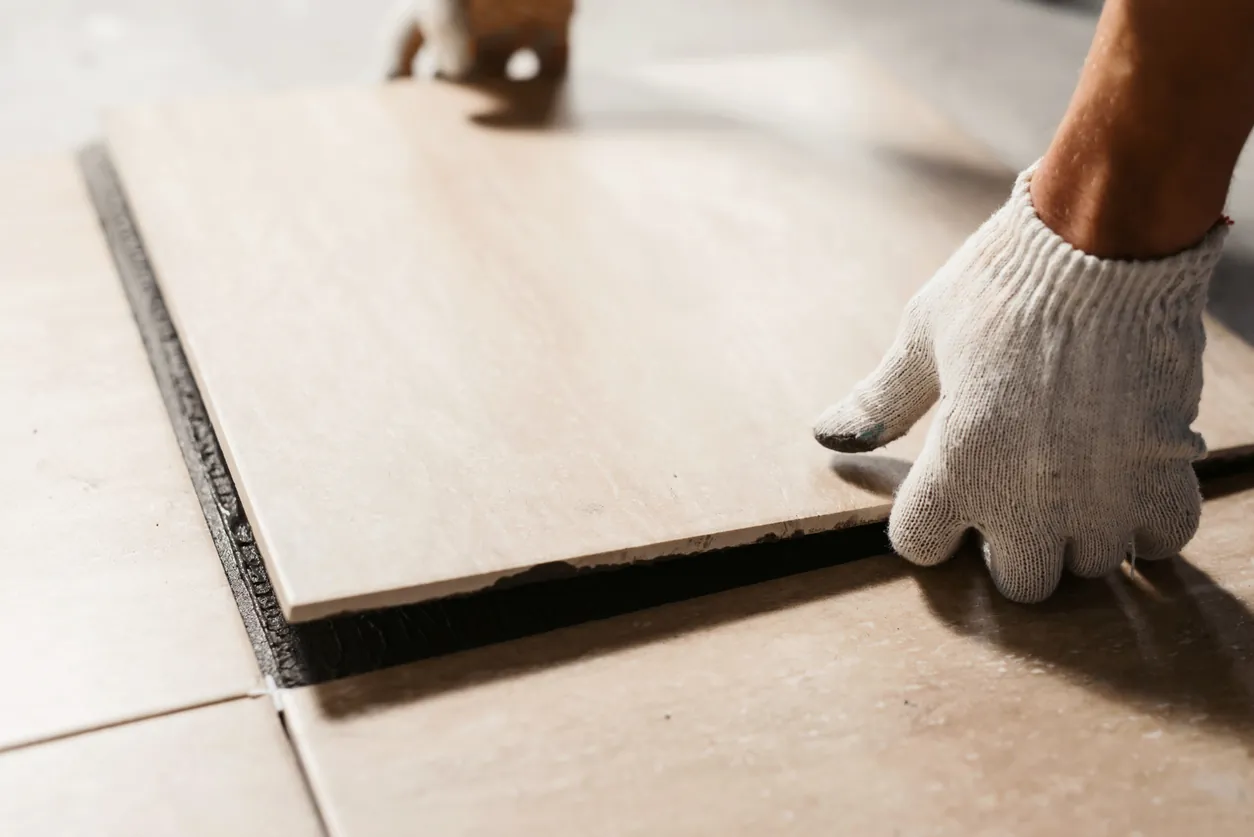 Slotting in the last, square tile onto a bathroom floor 