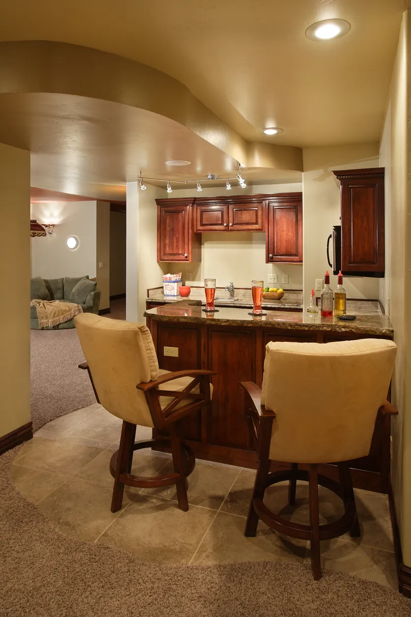 A small basement bar with two bar seats and two drinks on the counter